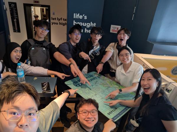 SherpaSec crew gathered around a signed SherpaSec community board